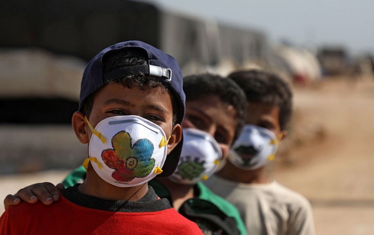 Displaced Syrian boys pose while wearing face masks decorated by artists during a COVID-19 awareness campaign at the Bardaqli camp in Dana, Idlib province, April 20, 2020. Photo: Aaref Watad / AFP