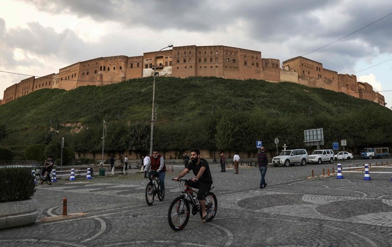 Men ride bicycles in front of the Erbil citadel, April 12, 2020. Photo: Safin Hamed / AFP 