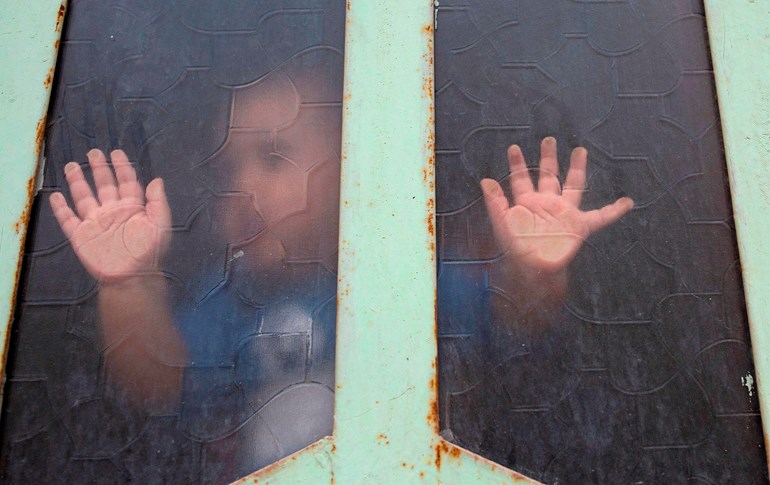 An Iraqi child looks out through a window pane amid confinement due to the COVID-19 pandemic, in the southern city of Basra, April 25, 2020. Photo: Hussein Faleh / AFP