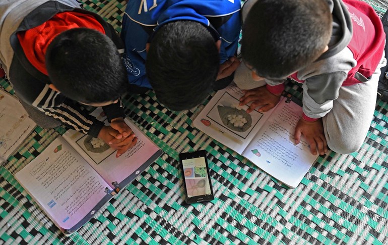 Displaced Syrian boys study online materials provided by their teachers on Whatsapp at the Muhammadiya camp, near Afrin, on April 19, 2020. Photo: Rami al Sayed/ AFP