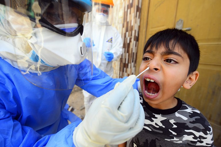 An Iraqi medic takes a nasal swab from a boy in Iraq's central shrine city of Najaf, April 20, 2020. Photo: Haidar Hamdani / AFP