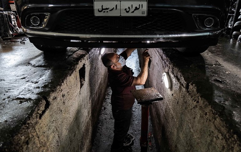 A mechanic, wearing a surgical mask due to the coronavirus pandemic, works on a vehicle being repaired at his garage in Erbil on April 30, 2020. Photo: Safin Hamed/ AFP