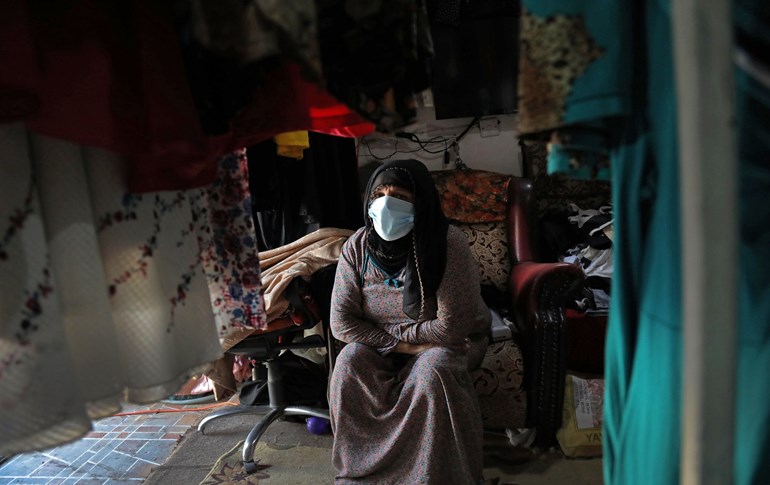 A clothing merchant, clad in protective mask due to the COVID-19 coronavirus pandemic, sits in her shop in Erbil,  on June 4, 2020. Photo: Safin Hamed/ AFP