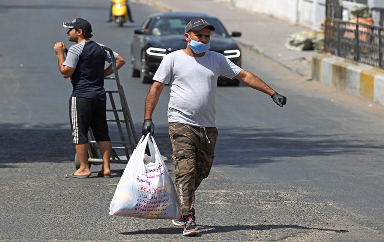 A mask-clad man crosses a street in Baghdad amid an extended curfew on June 8, 2020. Photo: Ahmad al-Rubaye/ AFP