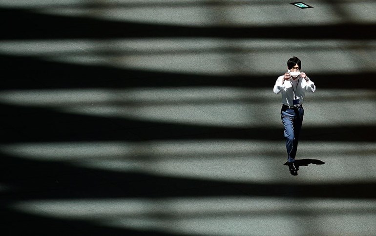 A man adjusts a protective mask to help curb the spread of the new coronavirus as he walks in the shade of a building Wednesday, June 10, 2020, in Tokyo. Photo: Eugene Hoshiko/AP