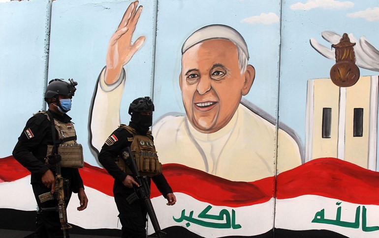 Members of the Iraqi special forces stand guard outside the Syriac Catholic Church of Our Lady of Deliverance, in front of a mural painting welcoming Pope Francis, in Baghdad, on March 4, 2021. Photo: Ahmad al-Rubaye/AFP