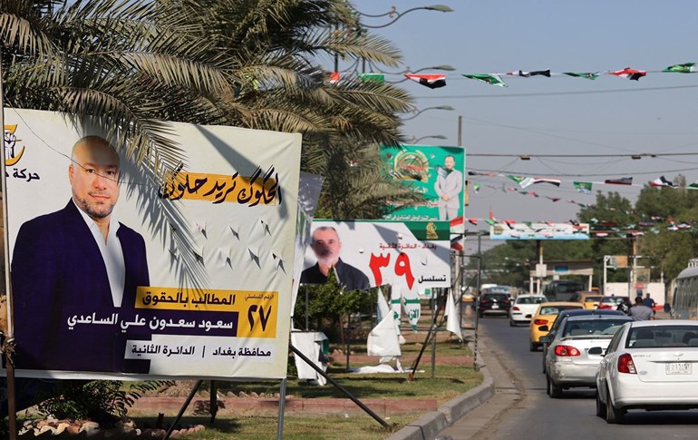 Cars drive in front of electoral billboards of candidates for the upcoming parliamentary elections, in the Iraqi capital Baghdad's Sadr City neighbourhood, on October 9, 2021. Photo: Ahmad al-Rubaye / AFP