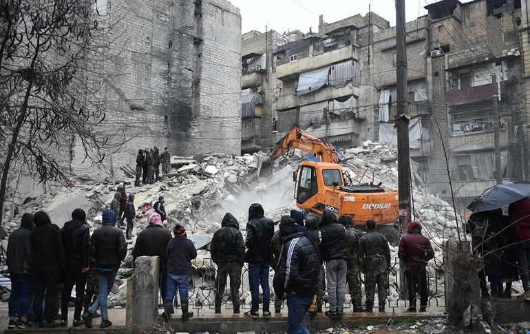 Onlookers watch as rescue teams look for survivors under the rubble of a collapsed building in Syria’s Aleppo on February 6, 2023. Photo: AFP