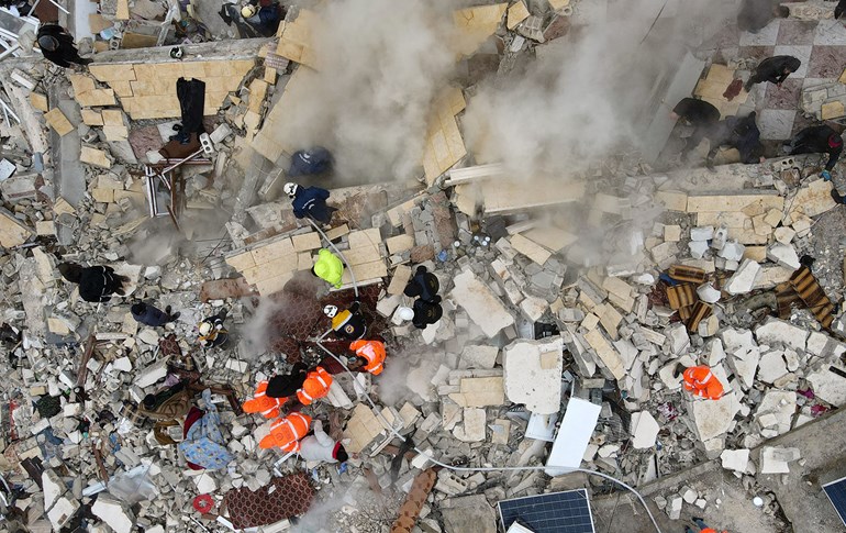 This aerial view shows residents helped by bulldozers, searching for victims and survivors in the rubble of collapsed buildings, following an earthquake in the town of Sarmada in the countryside of the northwestern Syrian Idlib province, early on February 6, 2023. Photo: Muhammad Haj Kadour/AFP