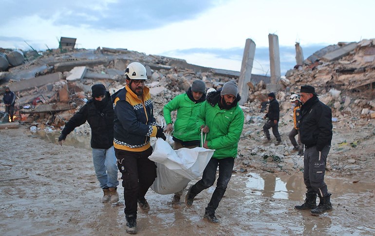 Syrian rescuers carry a body past the collapsed buildings on February 6, 2022 in the town of Sarmada, in Syria's rebel-held northwestern Idlib province. Photo: Aaref Watad/AFP 