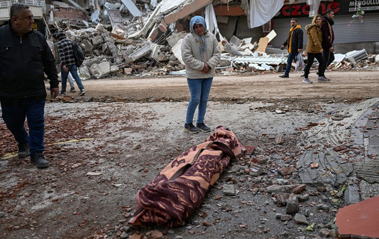 A woman weeps as she stands beside the body of one of the earthquake victims in Turkey’s Hatay on February 7, 2023. Photo: Bulent Kilic/AFP