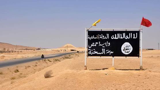 An ISIS poster in the central Syrian town of Sukhnah is adorned with the flags of pro-government fighters after the Syrian government took control of the area. File photo: AFP